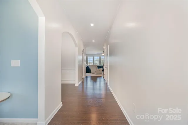 a view of a hallway with wooden floor and a bathroom
