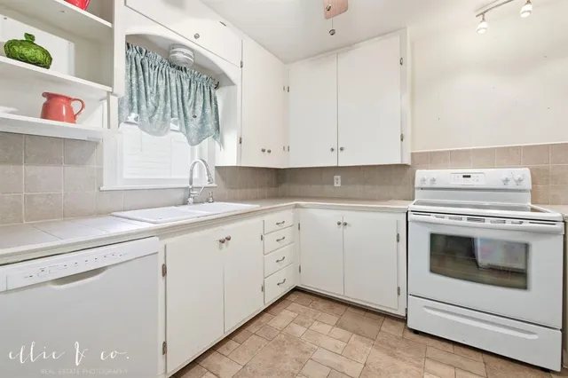a kitchen with granite countertop white cabinets and white appliances