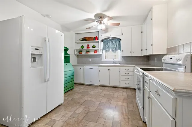 a kitchen with white cabinets and white appliances