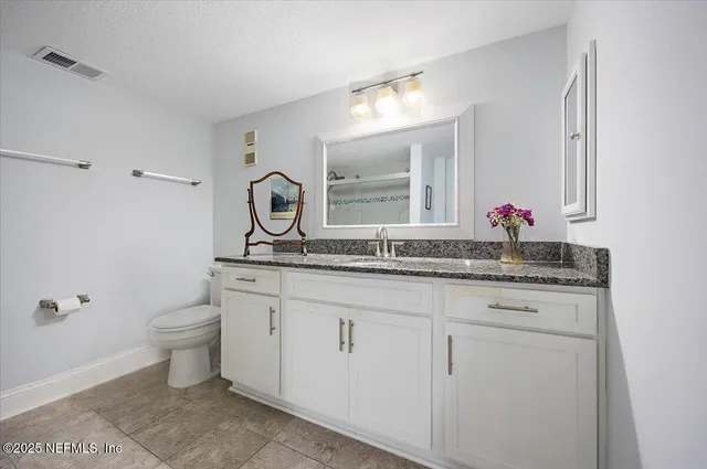 a bathroom with a granite countertop toilet sink and mirror