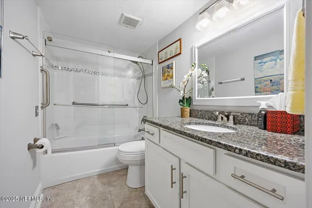 a bathroom with a granite countertop sink a toilet and shower