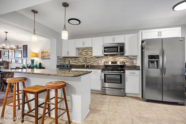 a kitchen with stainless steel appliances granite countertop a stove a sink and a refrigerator