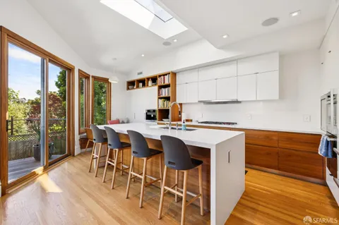 a kitchen with stainless steel appliances granite countertop a stove a refrigerator a sink and a dining table with wooden floor