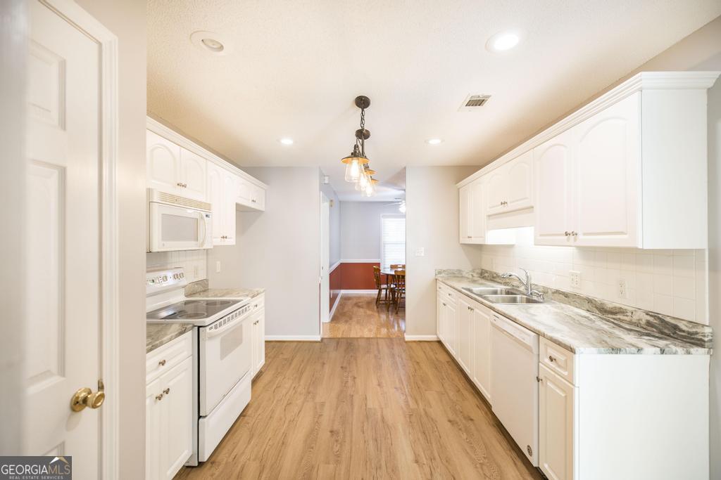 209 Mossy Ridge Warner Robins, GA 31088 - Photo 11 of 38 a large kitchen with kitchen island a stove a sink dishwasher and white cabinets with wooden floor