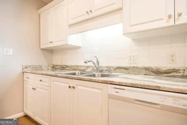 a kitchen with granite countertop white cabinets and a sink