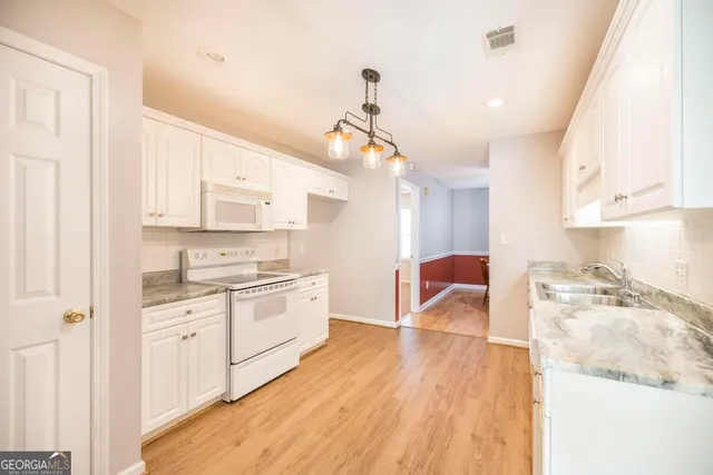 a kitchen with a sink a stove cabinets and wooden floor