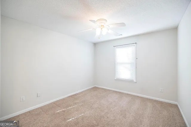 an empty room with a window and a chandelier fan