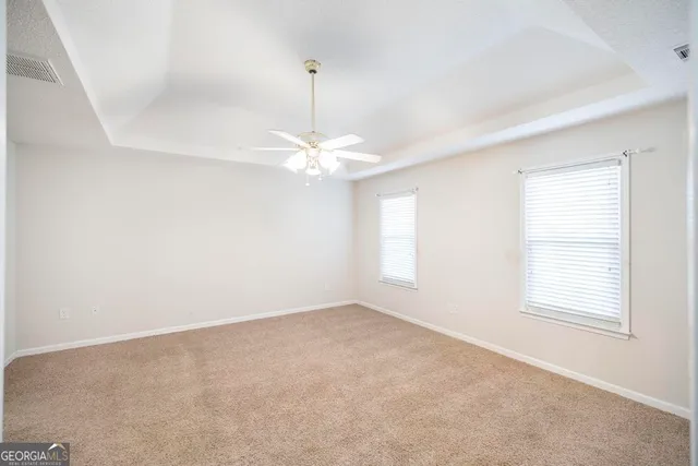 an empty room with a window and chandelier fan