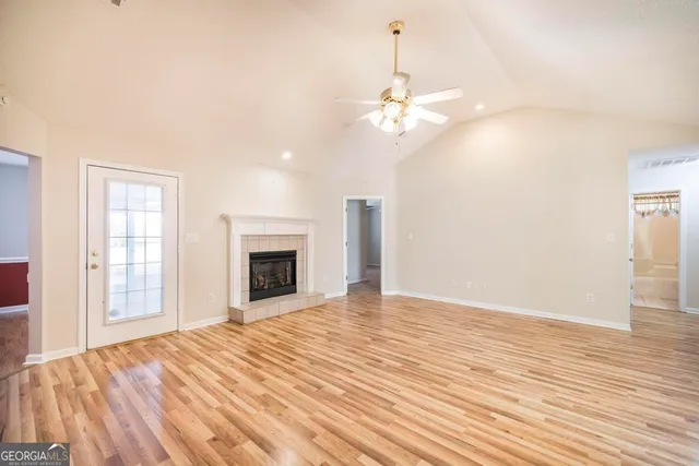 an empty room with wooden floor fan and windows