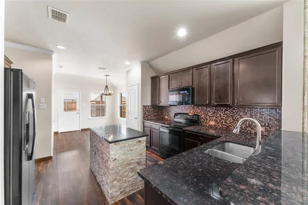 a kitchen with stainless steel appliances granite countertop a stove top oven a sink refrigerator and cabinets