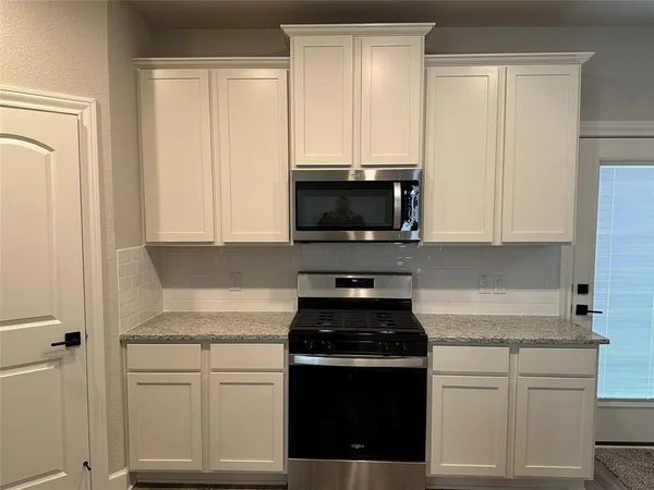 a kitchen with stainless steel appliances granite countertop white cabinets and a stove