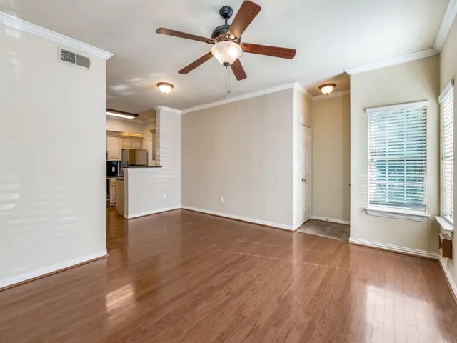 a view of empty room with wooden floor and fan