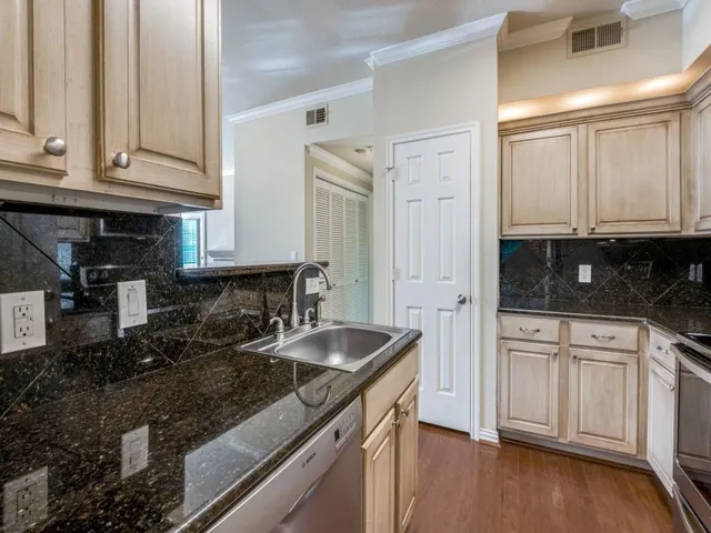 a kitchen with granite countertop a sink stainless steel appliances and cabinets