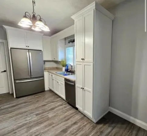 a kitchen with stainless steel appliances a refrigerator and a hard wood floor