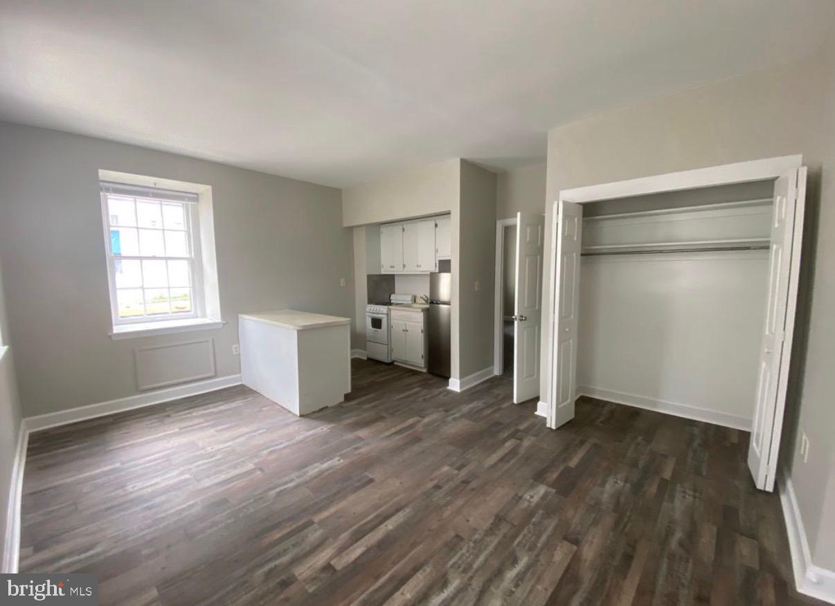 an empty room with wooden floor closet and windows