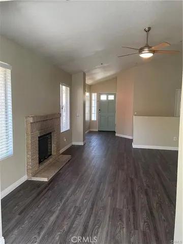 an empty room with wooden floor fireplace and windows