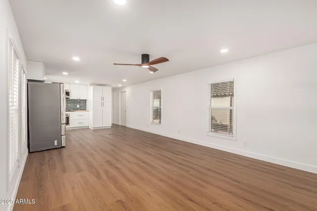 a view of an empty room with wooden floor and a window