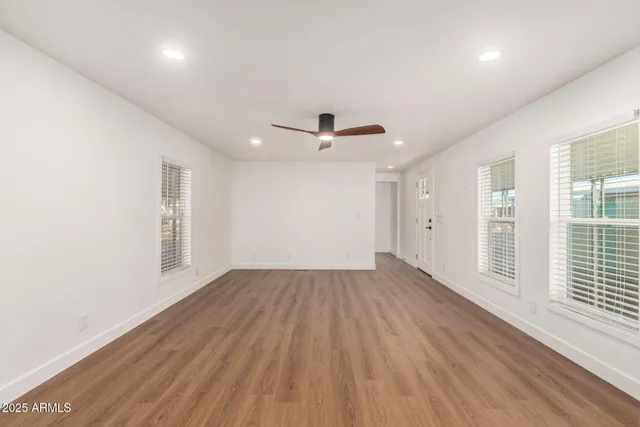 an empty room with wooden floor and windows