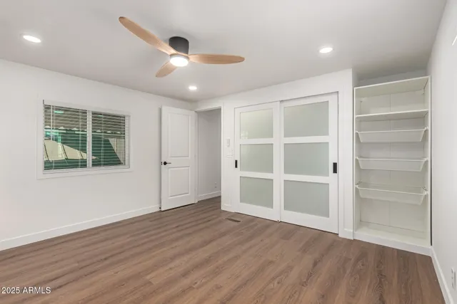 a view of an empty room with a window and wooden floor