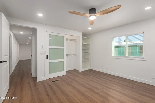 an empty room with wooden floor chandelier and windows