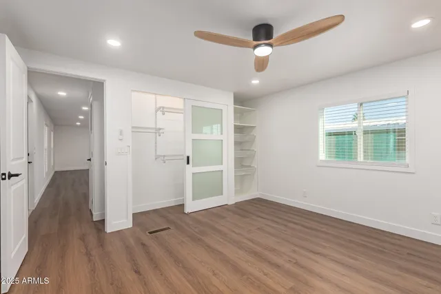 an empty room with wooden floor chandelier and windows