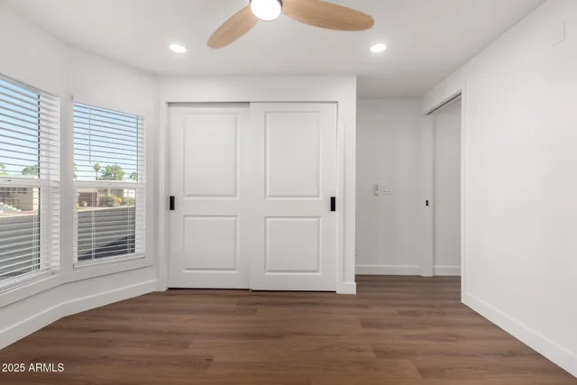 a view of empty room with wooden floor and fan