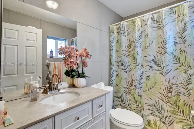 a bathroom with a granite countertop sink a toilet and a mirror