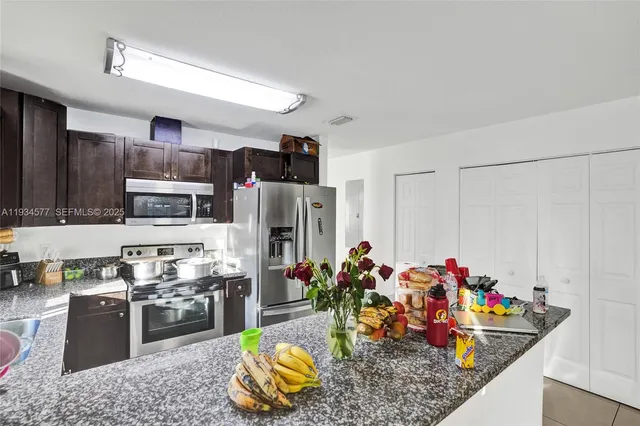 a kitchen with stainless steel appliances kitchen island granite countertop a stove refrigerator and cabinets