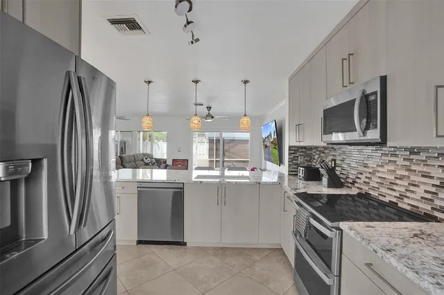 a kitchen with stainless steel appliances granite countertop a stove refrigerator sink and microwave