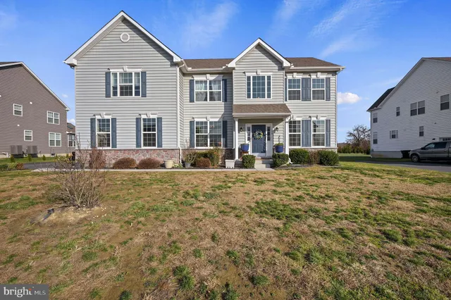 a front view of residential houses with yard and trees in the background