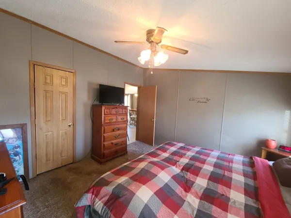 a bedroom with a bed and a flat tv screen on dresser
