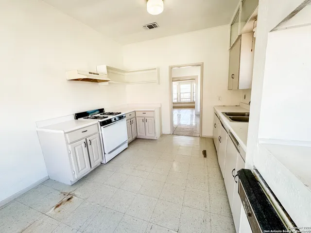 a kitchen with white cabinets and appliances