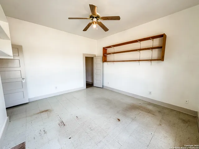 an empty room with a ceiling fan and window