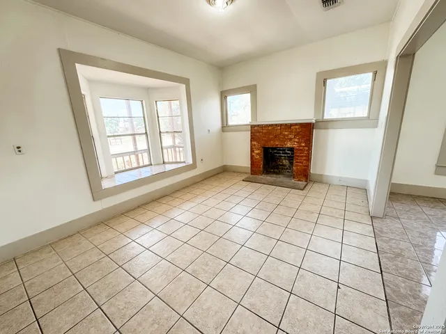 a view of an empty room with a fireplace and a window