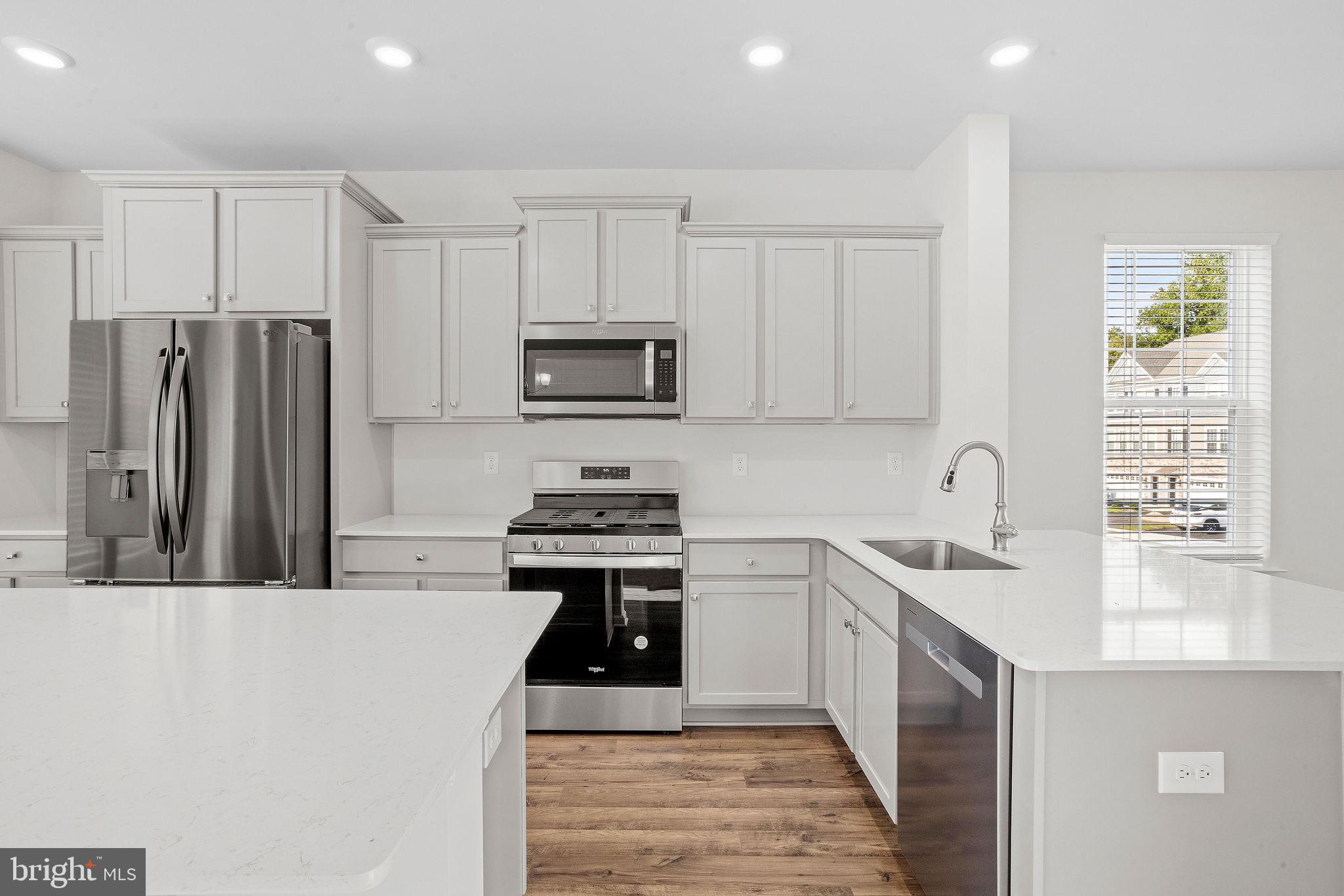 a kitchen with stainless steel appliances a sink a stove a refrigerator cabinets and a window