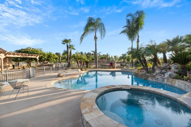 a view of a swimming pool with a lawn chairs under palm trees