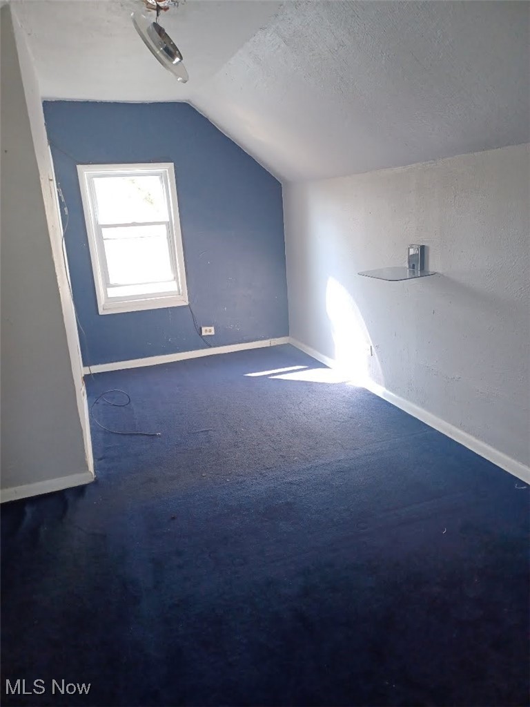 1656 Cliffview Road Cleveland, OH 44112 - Photo 3 of 4 Additional living space featuring baseboards, a textured ceiling, and vaulted ceiling