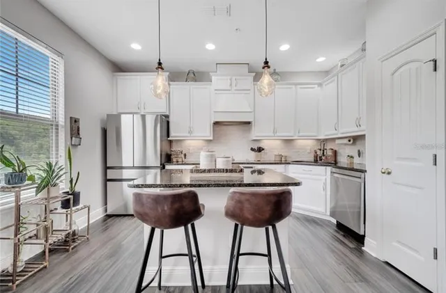 a kitchen with kitchen island white cabinets and stainless steel appliances