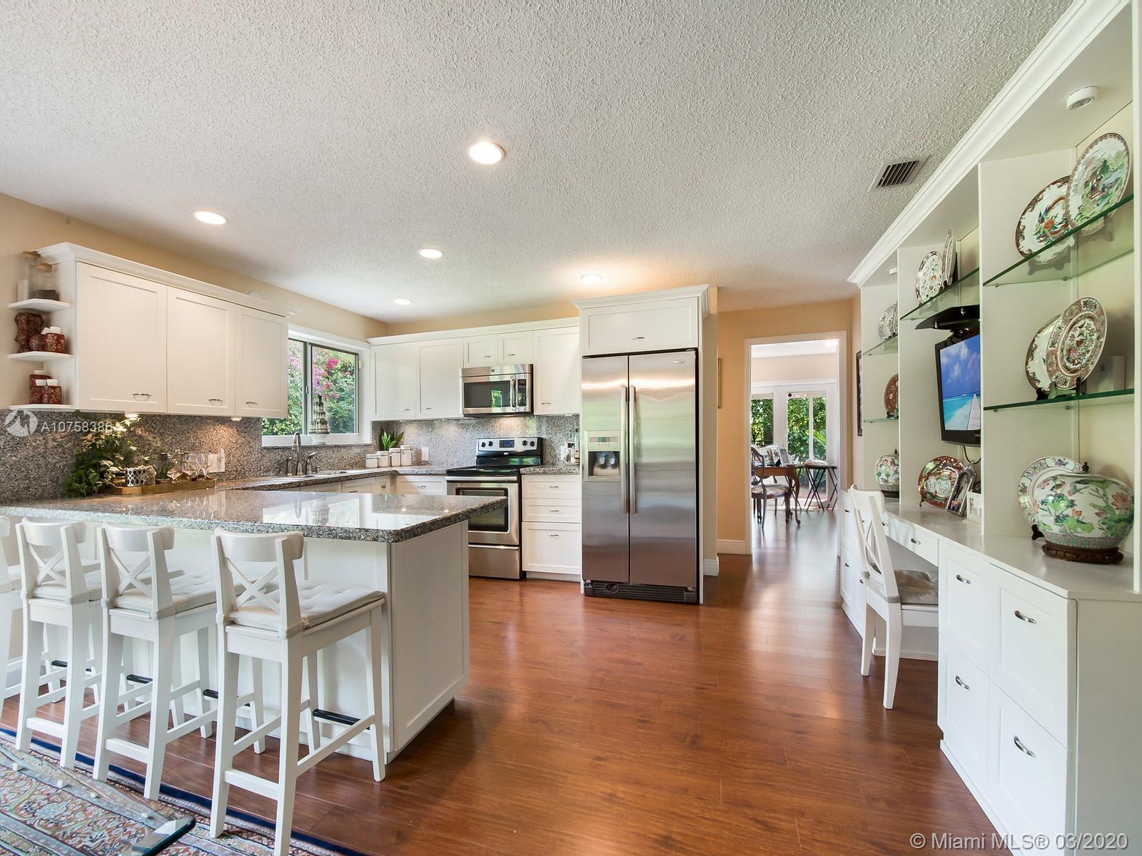 6701 Southwest 49th Terrace Miami, FL 33155 - Photo 7 of 24 a kitchen with stainless steel appliances kitchen island granite countertop a refrigerator a stove a sink and white cabinets with wooden floor