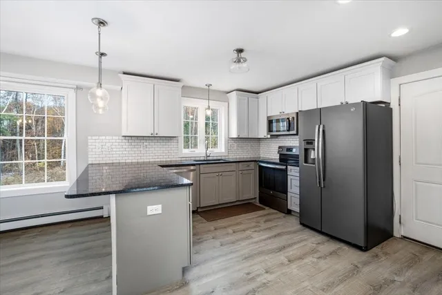 a kitchen with stainless steel appliances granite countertop a refrigerator a sink dishwasher a stove and white countertops with wooden floor