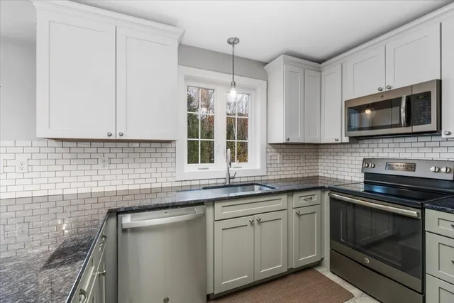 a kitchen with stainless steel appliances granite countertop a sink a stove a microwave and wooden cabinets