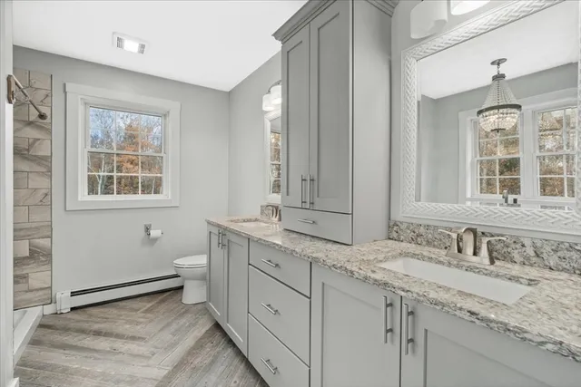 a bathroom with a granite countertop sink mirror and a toilet