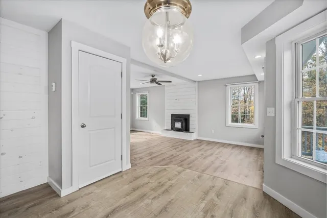an empty room with wooden floor chandelier and windows