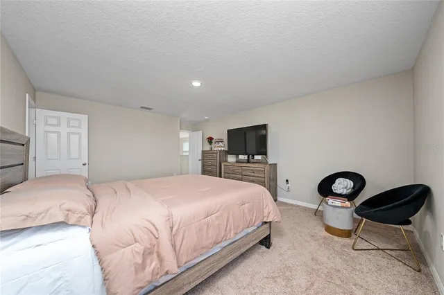 a bedroom with a bed a chair and a flat screen tv