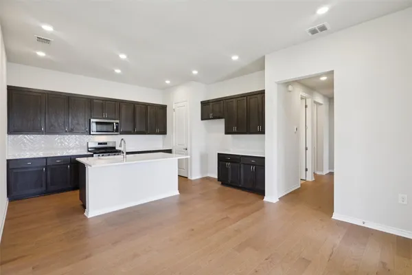 a large kitchen with a large counter top stainless steel appliances and cabinets