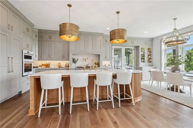 a dining room with wooden floor a chandelier a glass table and chairs
