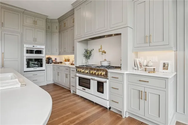 a kitchen with stainless steel appliances granite countertop a stove a sink and white cabinets