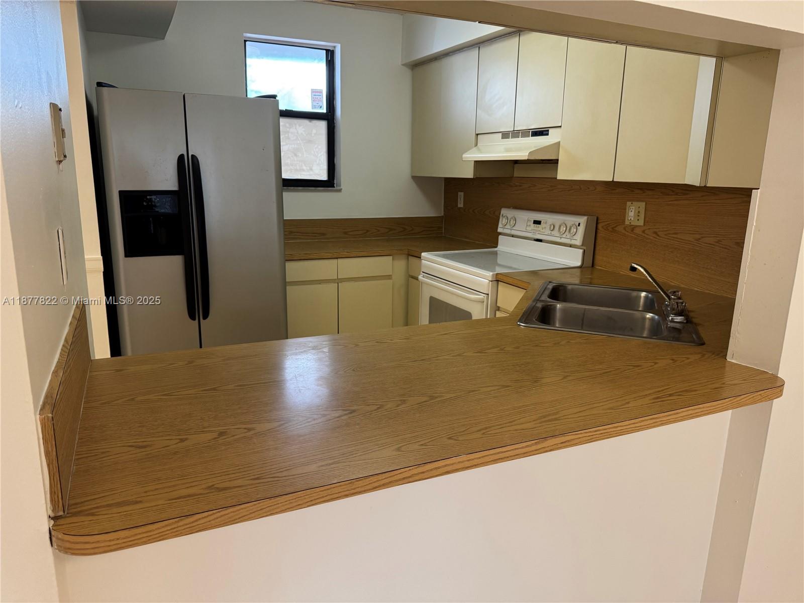 5765 West 25th Court, Unit 206 Hialeah, FL 33016 - Photo 7 of 12 a kitchen with stainless steel appliances granite countertop a sink refrigerator and microwave