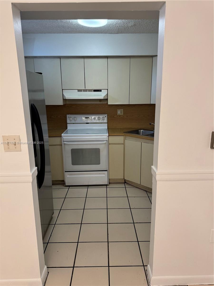 5765 West 25th Court, Unit 206 Hialeah, FL 33016 - Photo 8 of 12 a kitchen with granite countertop a stove a sink and a refrigerator