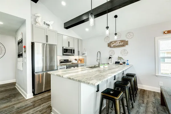 a kitchen with stainless steel appliances granite countertop a refrigerator a sink dishwasher a stove and a refrigerator with wooden floor